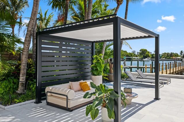 Black cabana-style pergola with white louvers beside a pool